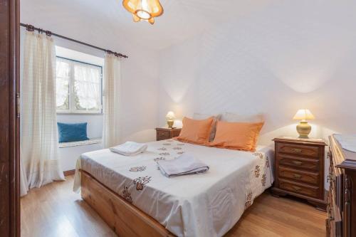 ein Schlafzimmer mit einem Bett mit weißen Laken und orangefarbenen Kissen in der Unterkunft Casa do Outeiro in Mondim de Basto