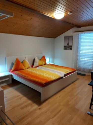 a bedroom with a bed with orange and yellow sheets at good bed biberist BIBERSOL in Biberist