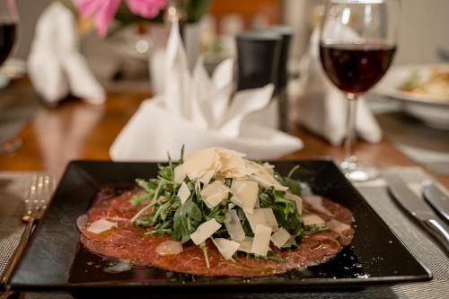 a plate of food on a table with a glass of wine at Hotel & Restaurant Tanne in Fischingen