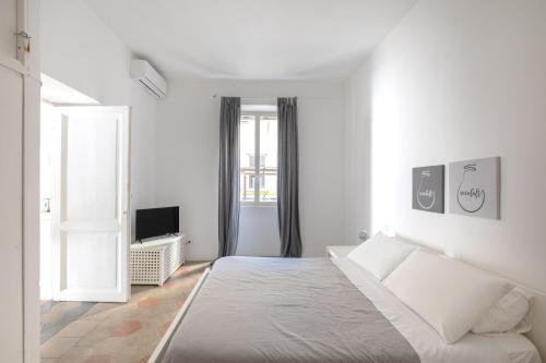 Habitación blanca con cama y TV en Vicoloft Sales en Roma