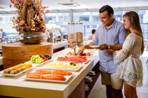 un hombre y una mujer preparando comida en un buffet en San Marino Suite Hotel en Maceió