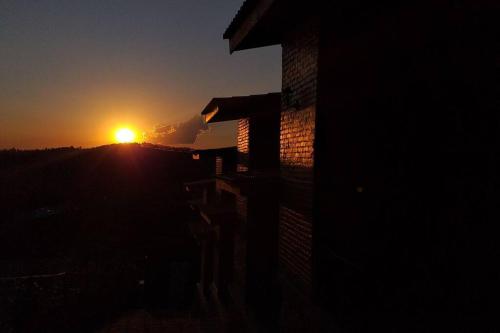 a building with the sunset in the background at La Villa Chalés in Serra Negra