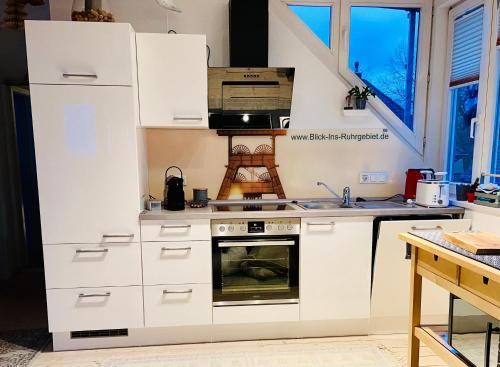 a kitchen with white cabinets and an oven at Blick ins Ruhrgebiet in Bochum