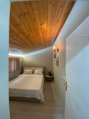 ein Schlafzimmer mit einem Bett mit Holzdecke in der Unterkunft Villa Elear in Korçë