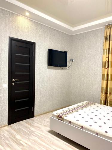 a bedroom with a bed and a flat screen tv on the wall at Apartment room-біля вокзалу-недалеко від центру in Lviv