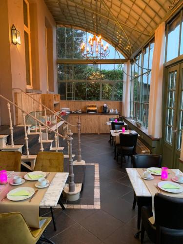 a restaurant with tables and chairs and a chandelier at Hotel Vredehof in Damme