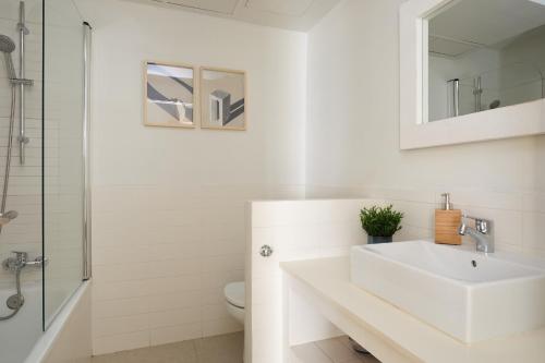 y baño blanco con lavabo y ducha. en Casa Cosi - Casanova 4, en Barcelona