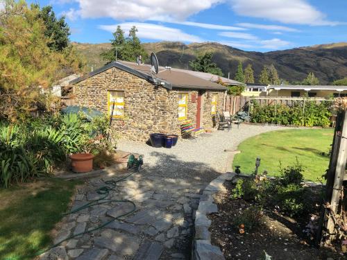 une maison en pierre avec un jardin et une cour dans l'établissement Fache Cottage, à Clyde