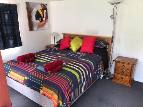um quarto com uma cama com lençóis e almofadas coloridos em Fache Cottage em Clyde