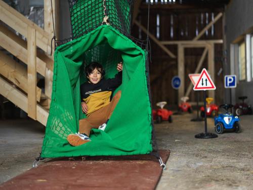 a young boy sitting in a green tent at Der Stern - Nachhaltiges Wirtshaus und Landhotel seit 1509 in Obsteig
