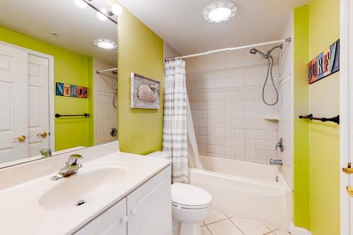 La salle de bains est pourvue de murs jaunes, d'un lavabo et de toilettes. dans l'établissement Island Cabana, à Ocean City