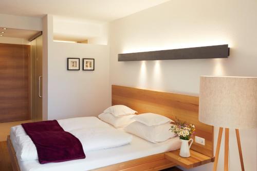 a bedroom with a bed with white sheets and a lamp at Der Stern - Nachhaltiges Wirtshaus und Landhotel seit 1509 in Obsteig
