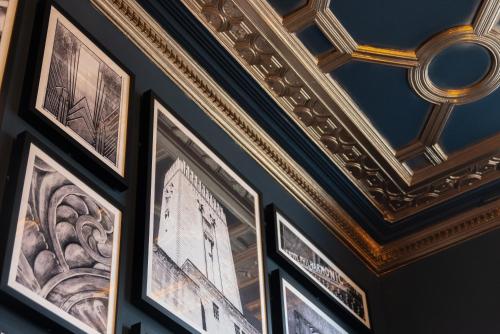 a group of framed pictures on a wall with a ceiling at 62 Castle Street Hotel in Liverpool