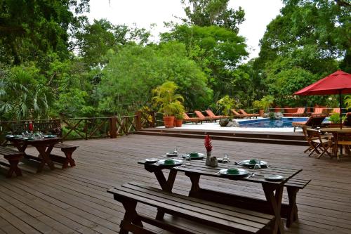 a wooden deck with two picnic tables and a pool at Hotel Jungle Lodge Tikal in Tikal