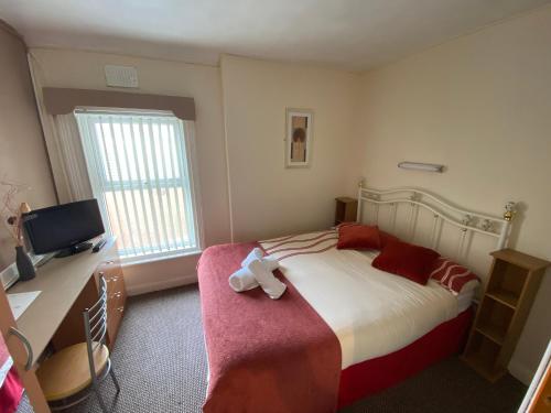 a bedroom with a bed and a desk and a television at White Moon Hotel in Blackpool