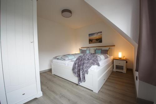 a bedroom with a white bed and a staircase at Midlum Stieglitz in Midlum