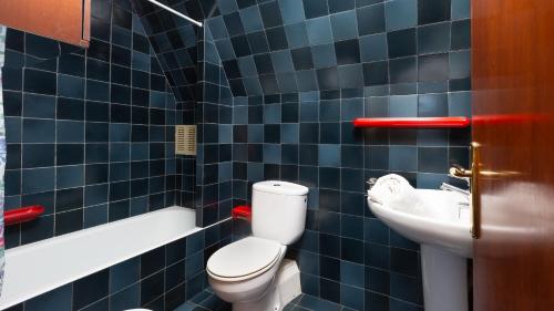 Un baño con azulejos azules, inodoro y lavabo. en 1Rosam01 Llafranc, en Llafranc