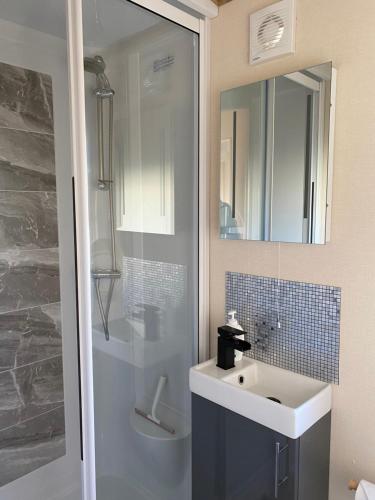 a bathroom with a sink and a shower with a mirror at Serendipity Holiday Home not for use by contractors in Penrith