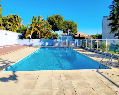une piscine avec une clôture et des palmiers dans l'établissement Bandol - Résidence Premium jardin, piscine et garage, à Bandol