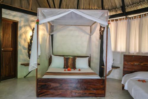 a bedroom with a canopy bed with white curtains at Sublime by Playa la Roca EcoHotel in Palomino