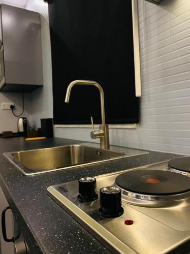 a kitchen counter with a sink and a stove with two cups at Elite Corner Apartment in Ţāb Kirā‘