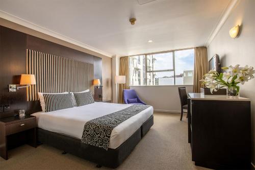 惠靈頓的住宿－美居惠靈頓貝爾塔斯曼酒店，酒店客房设有一张大床、一张桌子和一张桌子。