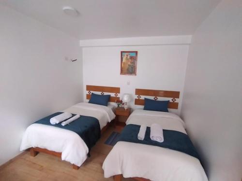 two beds in a room with white walls at Qente Wings in Ollantaytambo
