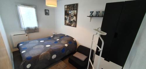 a small bedroom with a bed and a window at Résidence Front de mer Cabourg - Accès direct plage in Cabourg
