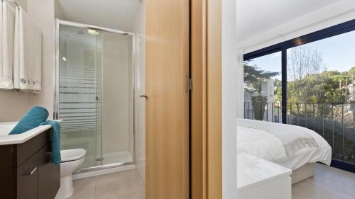 een badkamer met een douche, een bed en een raam bij Apartment Sta Rosa1 - Llafranc in Llafranc