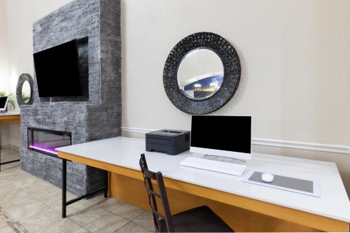 a desk with a computer and a mirror on a wall at La Quinta by Wyndham Garland Harbor Point in Garland