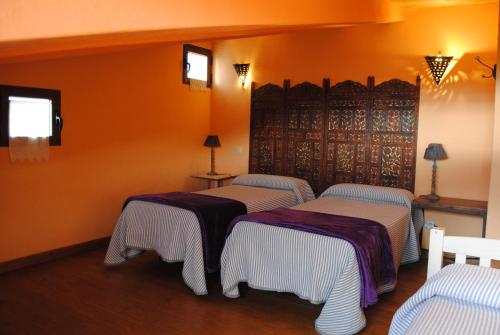 two beds in a room with orange walls at Alojamiento Rural Fuente del Arca (Prádena del Rincón) in Prádena del Rincón