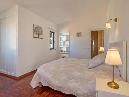 ein Schlafzimmer mit einem Bett und einer Lampe auf einem Tisch in der Unterkunft Carvoeiro Peaceful Villa with Pool in Carvoeiro
