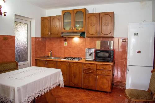 een keuken met houten kasten, een magnetron en een koelkast bij Cabana Liliana in Arieşeni