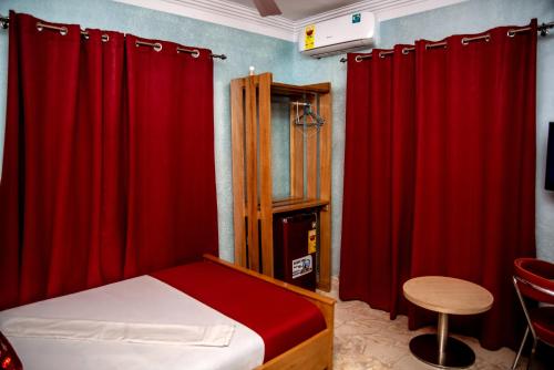 a bedroom with red curtains and a bed with a stool at Homey Lodge in Kumasi