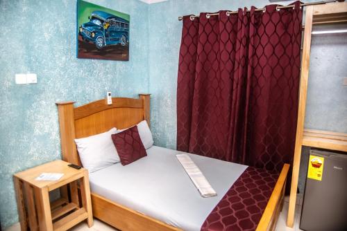 a small bedroom with a bed with a red curtain at Homey Lodge in Kumasi