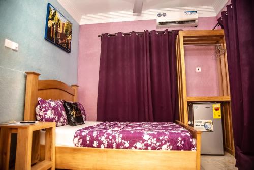a bedroom with a bed and a purple curtain at Homey Lodge in Kumasi