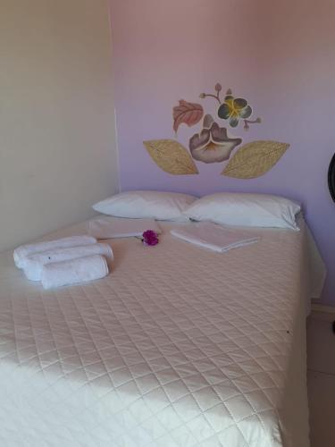 a bedroom with a bed with white sheets and flowers on it at Pousada Recanto das Flores in Praia de Moitas