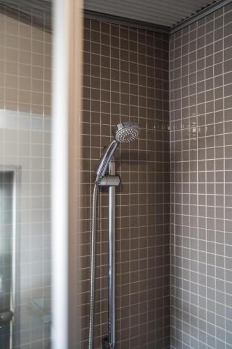 a shower in a bathroom with brown tiles at The Governess in Launceston