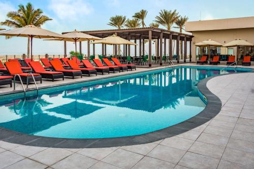 a pool with chairs and umbrellas at a resort at Park Inn by Radisson Hotel and Residence Duqm in Duqm