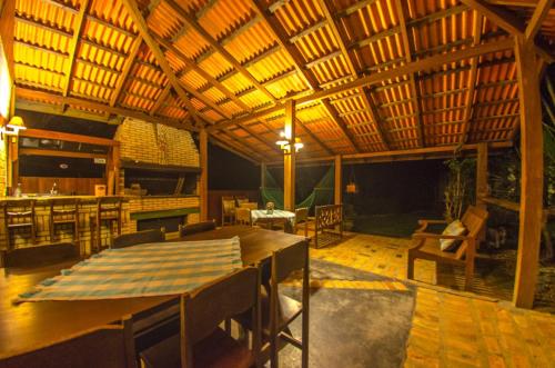 a restaurant with a wooden ceiling and a table and chairs at Pousada Sunset in Praia do Rosa