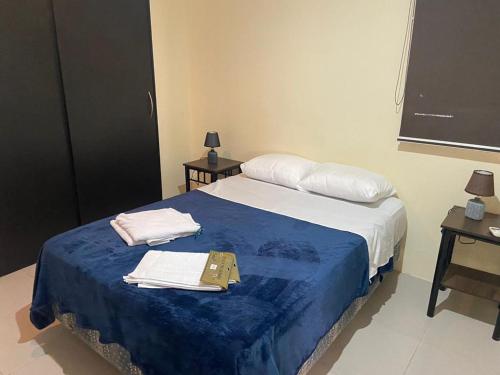 a bedroom with a bed with a blue blanket and towels at The Heights in Montañita in Montañita