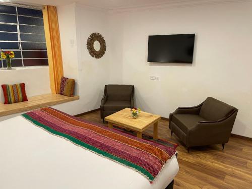 a living room with two chairs and a table and a television at CASA CRISTOBAL Siete Cuartones in Cusco
