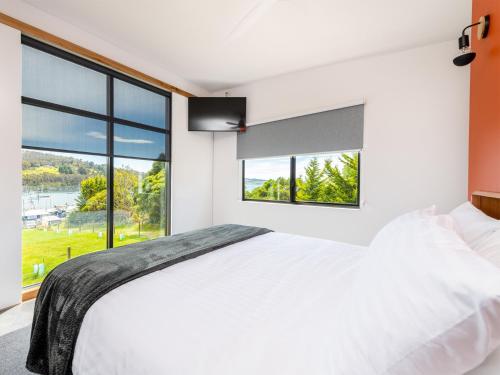 Schlafzimmer mit einem großen weißen Bett und großen Fenstern in der Unterkunft Little Oyster Bayview in Kettering