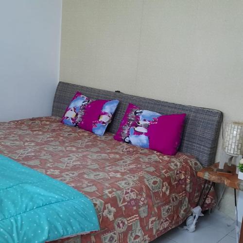 a bed with pink and blue pillows on it at Blesshomestay Samosir in Sinabono