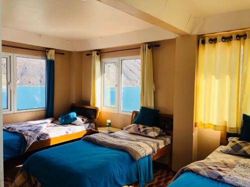 a room with two beds and two windows at Gokyo Thanka Inn in Khumjung