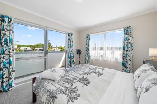 a bedroom with a bed and a large window at Hunia Haven - Himatangi Beach Holiday Home in Oroua Downs