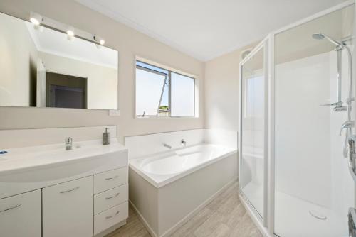 a white bathroom with two sinks and a shower at Hunia Haven - Himatangi Beach Holiday Home in Oroua Downs