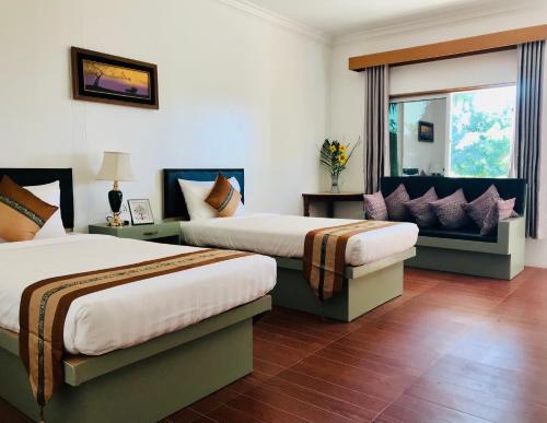 ein Hotelzimmer mit 2 Betten und einem Fenster in der Unterkunft E-Outfitting Royal Inn Bagan in Myene