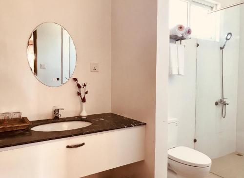 ein Badezimmer mit einem Waschbecken, einem WC und einem Spiegel in der Unterkunft E-Outfitting Royal Inn Bagan in Myene