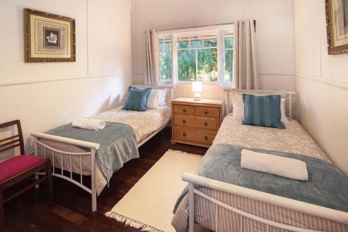 two twin beds in a room with a window at Heritage Cottage Margaret River in Margaret River Town